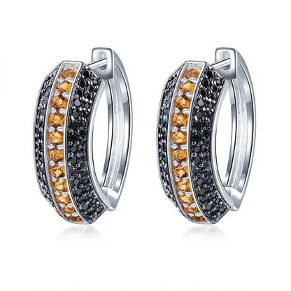 Pair of silver hoop earrings with orange and black gemstones on a white background