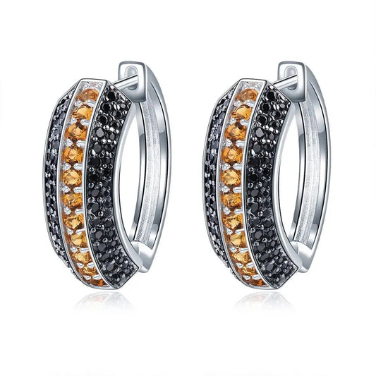 Pair of silver hoop earrings with orange and black gemstones on a white background